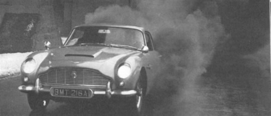 "Nunca nas alcanzarás" , Goldfinger, parece haber dicho el agente 007 al escapar envuelto en humo de sus tenaces perseguidores en este Aston Martin especial. Un redactor de MP probó el generador de humo instalado debajo del auto obteniendo resultados verdaderamente espectaculares